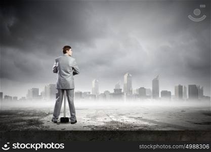 Man with hammer. Young businessman with hammer and city at background