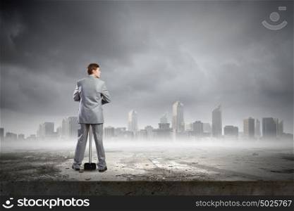 Man with hammer. Young businessman with hammer and city at background