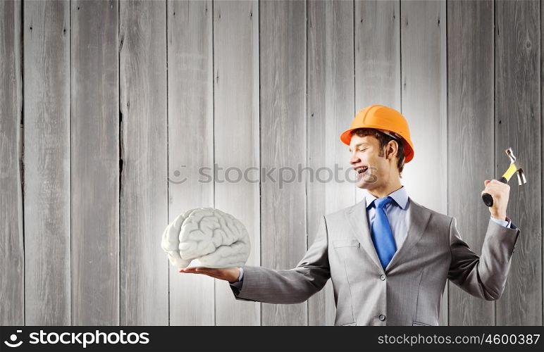 Man with hammer. Young businessman with hammer and human brain in hand