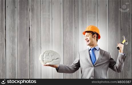 Man with hammer. Young businessman with hammer and human brain in hand
