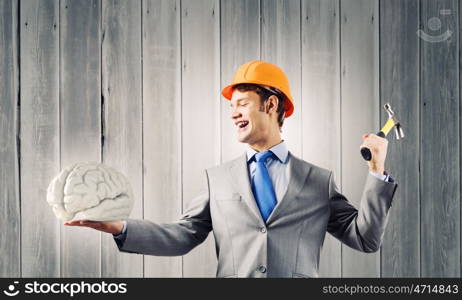 Man with hammer. Young businessman with hammer and human brain in hand