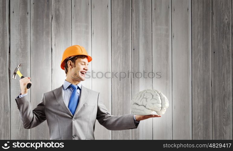 Man with hammer. Young businessman with hammer and human brain in hand