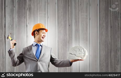 Man with hammer. Young businessman with hammer and human brain in hand