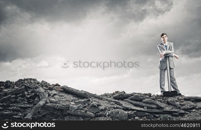 Man with hammer. Young businessman with hammer standing on ruins