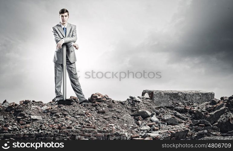 Man with hammer. Young businessman with hammer standing on ruins