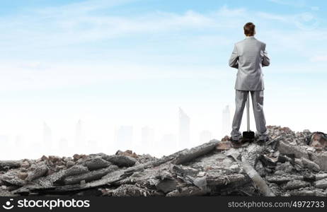 Man with hammer. Young businessman with hammer standing on ruins