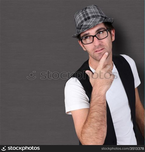 Man with hand on chin standing on dark background