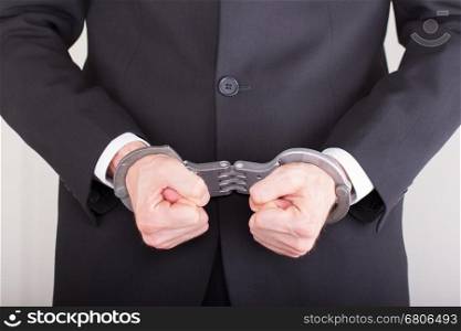 Man with handcuffs, business suit, focus on the handcuffs