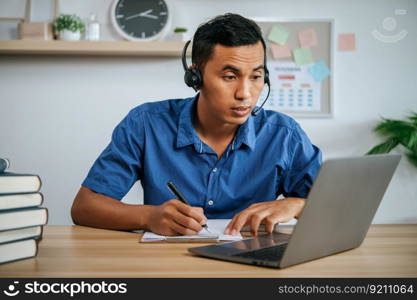man with headphones working in office with papers and laptop on desk