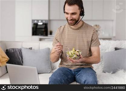 man with headset eating while attending video call