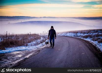 man with his dog in foggy winter landscape at sunset