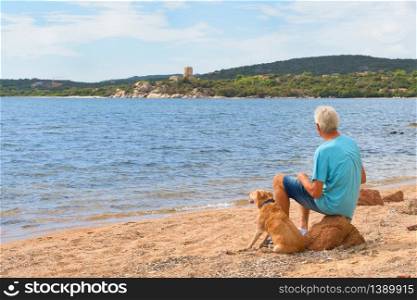 Man with his dog resting at the South of Corsica near Bonifacio with Genoese tower at the coast