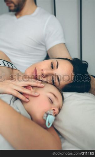 Man with his wife watching over his son while sleeping. Man with wife watching his sleeping son