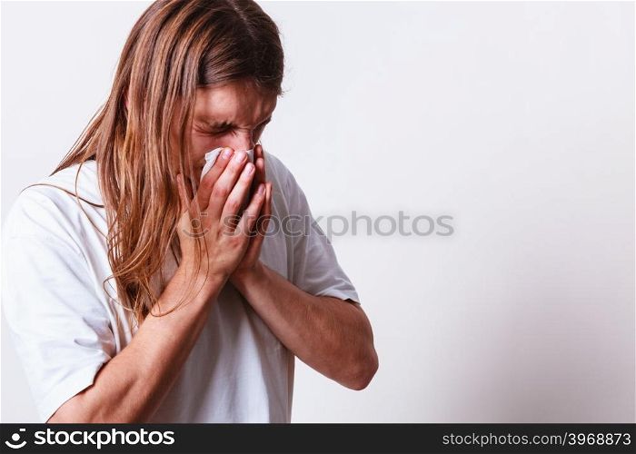 Man with hygienic tissue. Allergy and cold concept. Young long haired sick man with hygienic tissue. Guy blowing nose.
