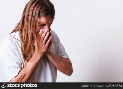 Man with hygienic tissue. Allergy and cold concept. Young long haired sick man with hygienic tissue. Guy blowing nose.
