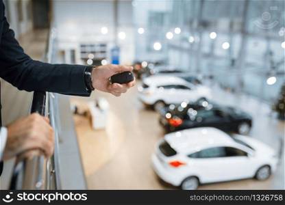 Man with keys from his new transport in car dealership. Customer in new vehicle showroom, male person buying automobile, auto dealer business. Man with keys from his transport in car dealership