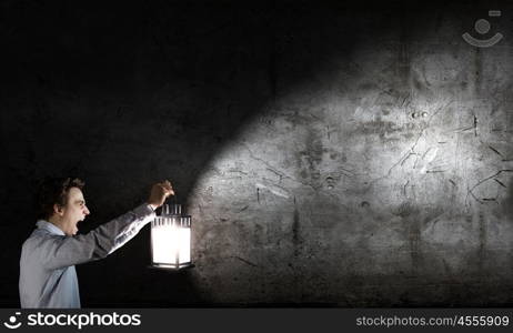 Man with lantern. Young handsome businessman walking in darkness with lantern