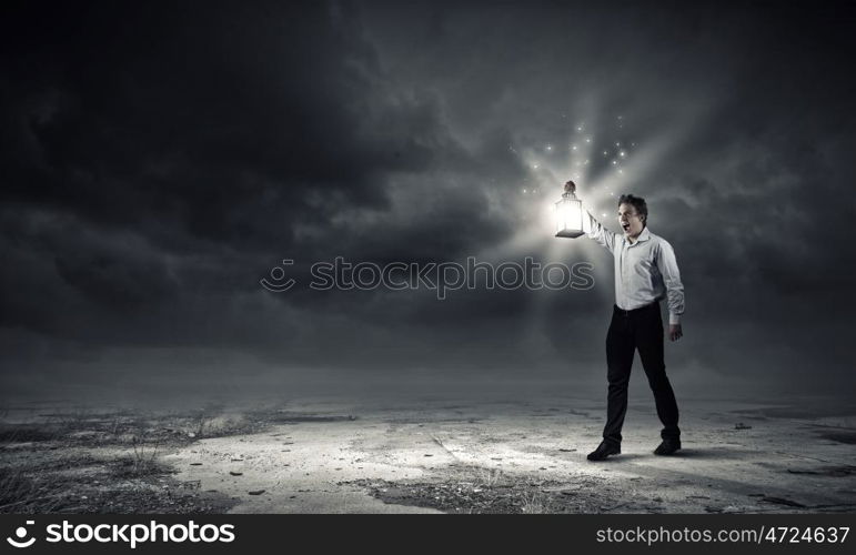 Man with lantern. Young handsome businessman walking in darkness with lantern