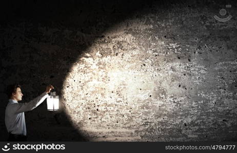 Man with lantern. Young handsome businessman walking in darkness with lantern