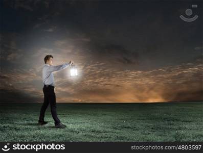 Man with lantern. Young handsome businessman walking in darkness with lantern