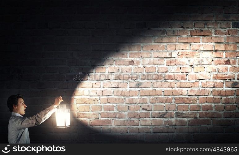 Man with lantern. Young handsome businessman walking in darkness with lantern