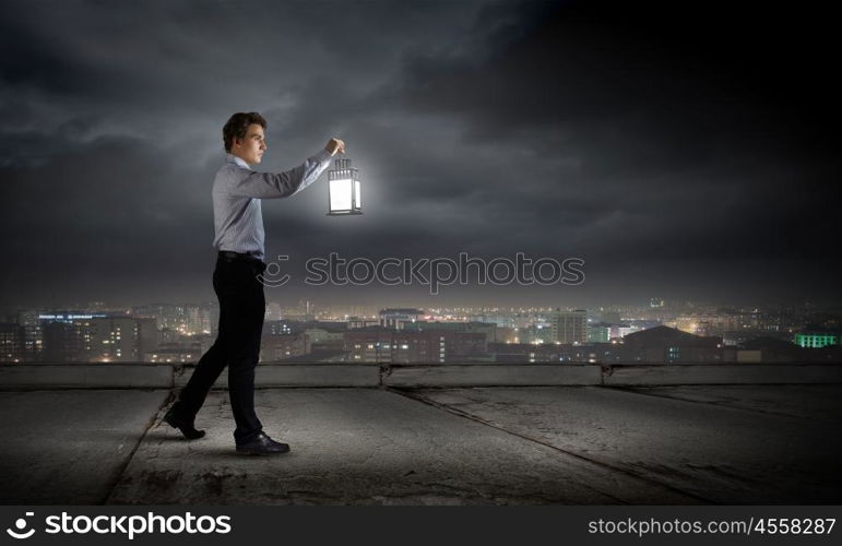 Man with lantern. Young handsome businessman walking with lantern in darkness