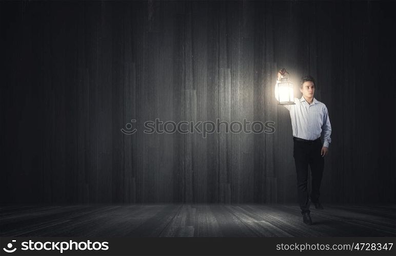 Man with lantern. Young handsome businessman walking with lantern in darkness