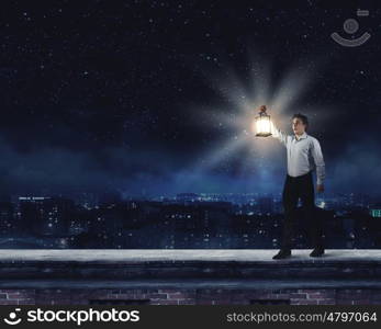 Man with lantern. Young handsome businessman walking with lantern in darkness