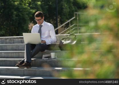 Man with laptop and coffee at summer park on bright day
