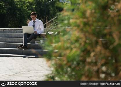 Man with laptop at summer park on bright day