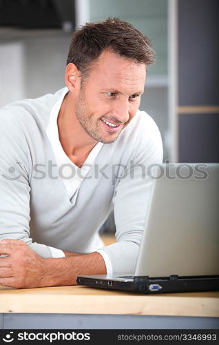 Man with laptop computer in kitchen
