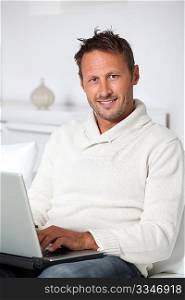 Man with laptop computer sitting in sofa