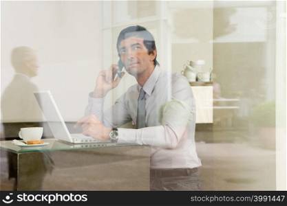 Man with laptop in coffee bar, View through window)