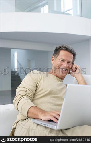 Man with laptop in living room smiling portrait
