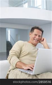 Man with laptop in living room smiling portrait