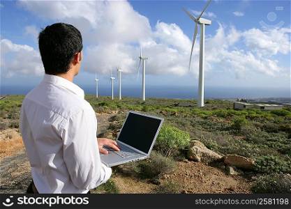 Man with laptop in wind farm