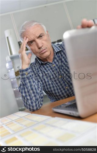 Man with laptop, looking troubled