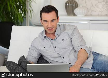 Man with laptop lying on a couch