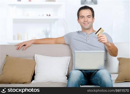 man with laptop on his lap holding card