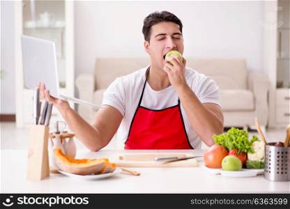 Man with laptop preparing food at the kitchen
