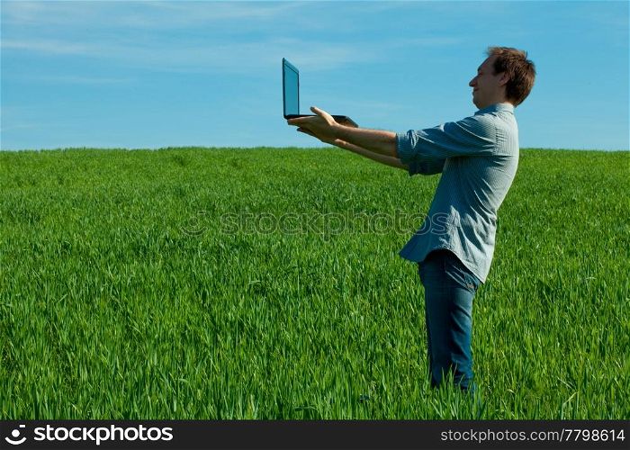 man with laptop standing in a field