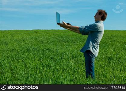 man with laptop standing in a field