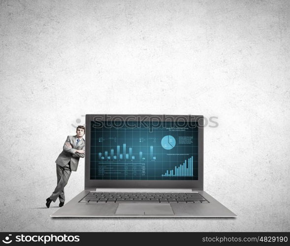 Man with laptop. Young confident businessman leaning on big laptop