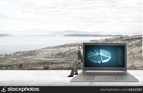 Man with laptop. Young confident businessman leaning on big laptop