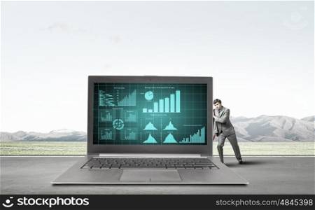 Man with laptop. Young confident businessman leaning on big laptop