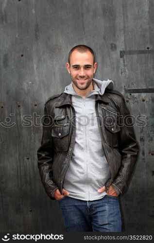 Man with leather jacket standing on metal door