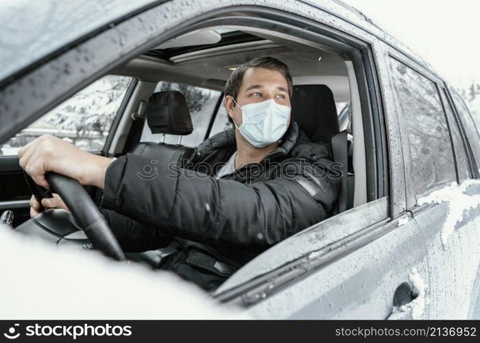 man with medical mask driving car road trip