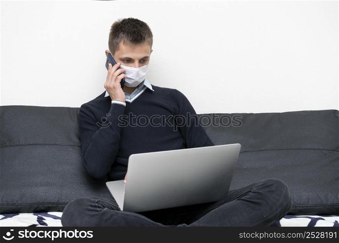 man with medical mask using laptop smartphone
