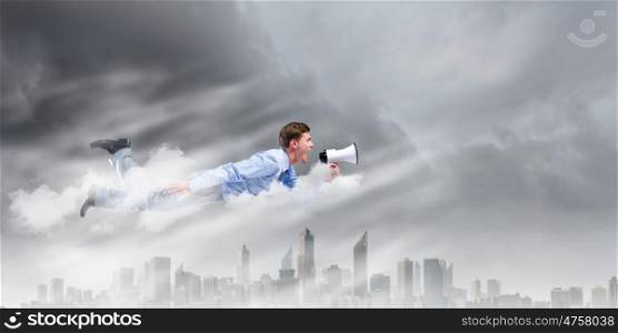 Man with megaphone. Young businessman with megaphone flying high in sky