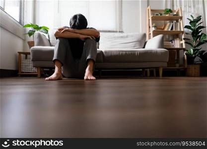 Man with mental health problem sitting on floor to resting head on his arms with depressed emotion.